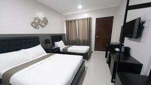 Habitación de hotel con dos camas, un televisor, un escritorio y una puerta.