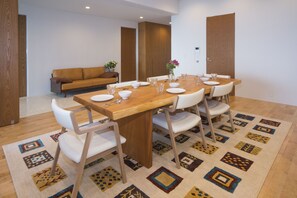A dining area with a wooden table, white chairs, and a patterned rug. - Onnason vacation rental L (Onna)