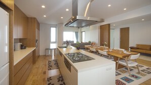 Een moderne keuken met een centraal eiland, houten kastjes en een eethoek met een tafel en stoelen.