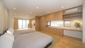 Een moderne slaapkamer met een groot bed, inbouwkasten en een raam met zonwering.
