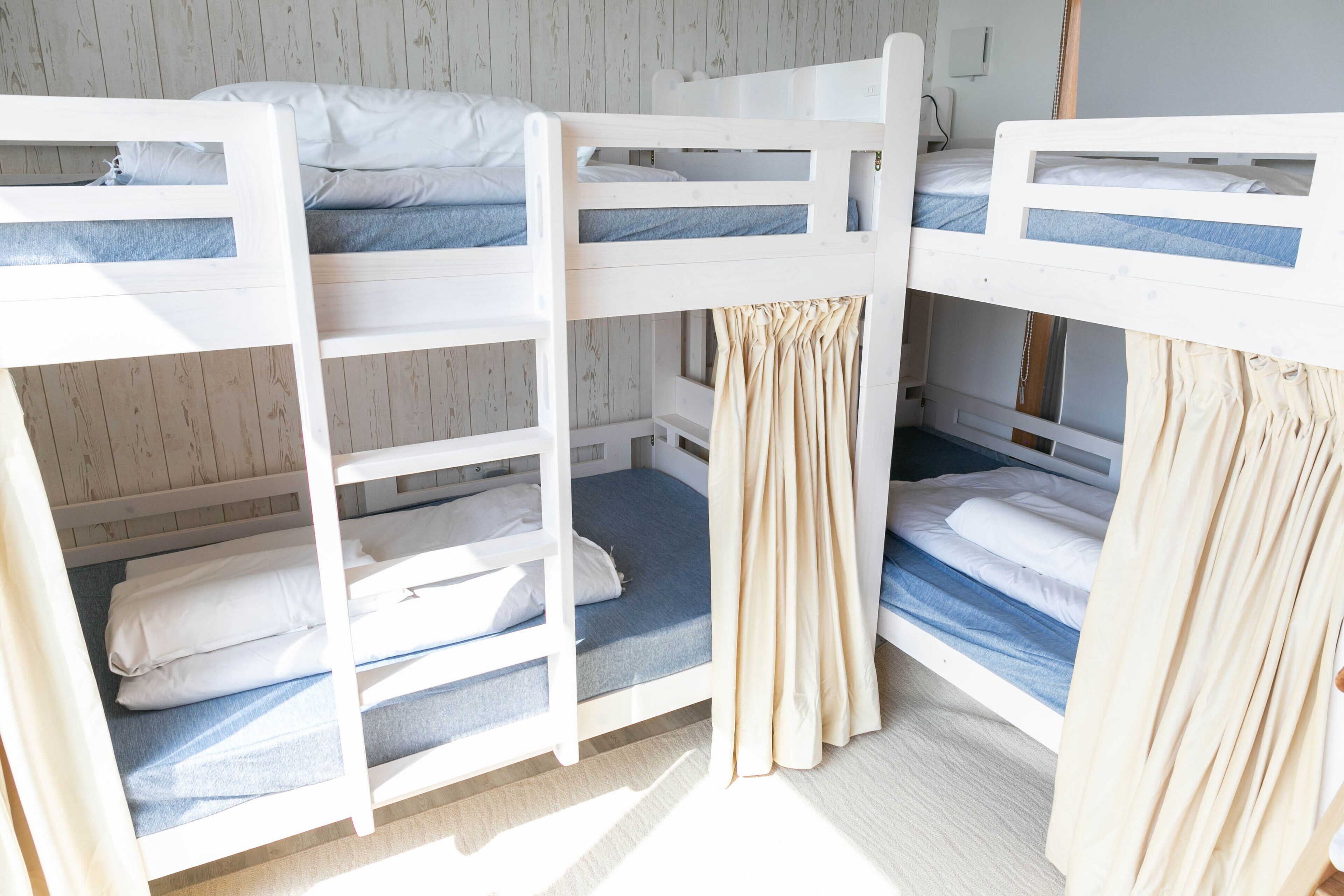 Etagenbetten mit Vorhängen, Holzboden und eine helle Wand.