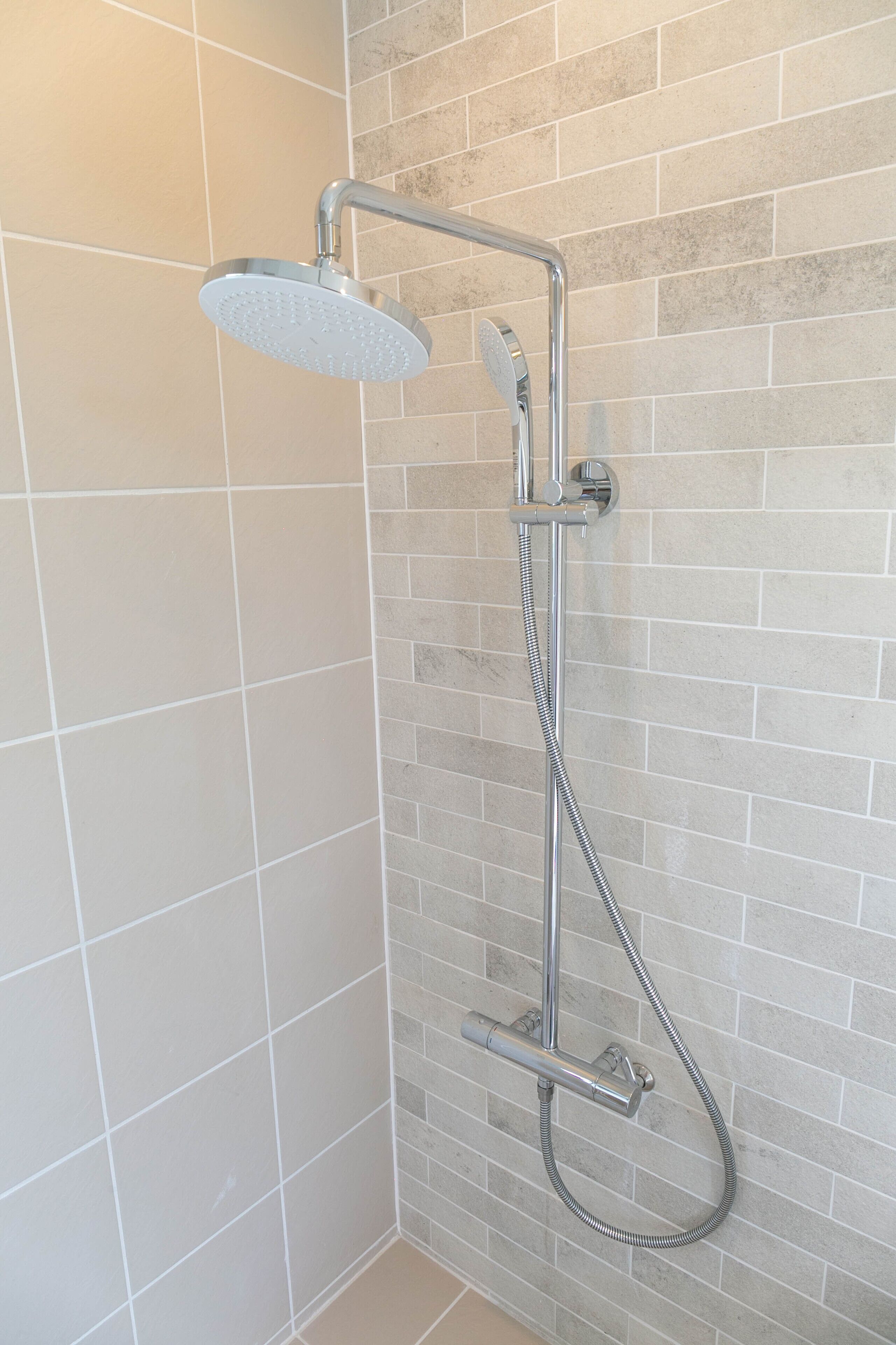 A shower with a handheld showerhead and a flexible hose.