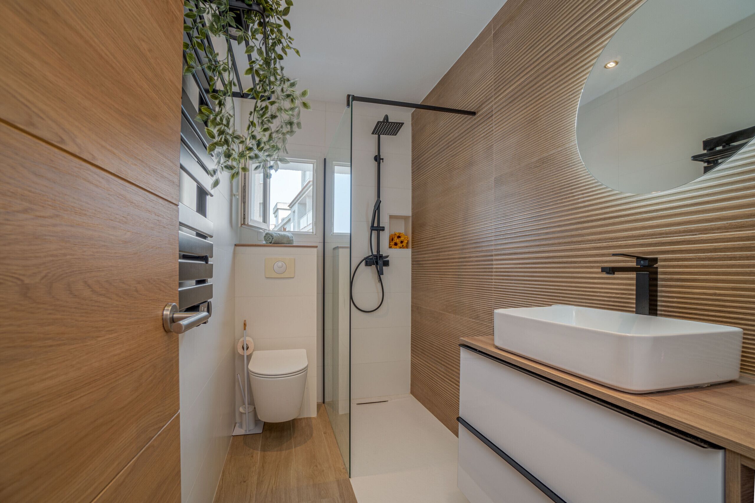 Une salle de bain moderne avec un meuble-lavabo en bois, une douche et des toilettes.