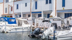 Een jachthaven met boten afgemeerd voor witte gebouwen met blauwe luiken.