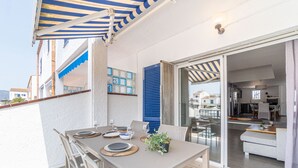 Een balkon met een eettafel, een schuifdeur naar een woongedeelte en een uitzicht op de omliggende gebouwen.