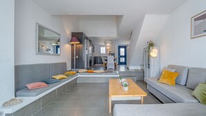 Een moderne woonkamer met een grijze bank, een houten salontafel en een bankje met kussens.