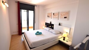 Quarto moderno com cama, mesa de cabeceira, luminária e obra de arte na parede.