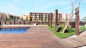 Um deck de madeira que leva a uma piscina, com vista para edifícios residenciais altos ao fundo.