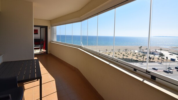Uma varanda com vista para a praia e estacionamento.