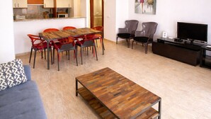 Ein modernes Wohnzimmer mit Essbereich, einer Couch, einem Couchtisch, einem Fernseher und einem Deckenventilator.