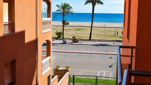 Blick vom Balkon auf einen Parkplatz, einen Strand und den Ozean.