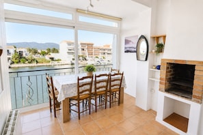 Un balcon avec une table et des chaises, une cheminée et une vue sur un port de plaisance avec des bâtiments.