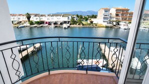 Un balcon avec vue sur une marina, des bateaux et des bâtiments en arrière-plan.