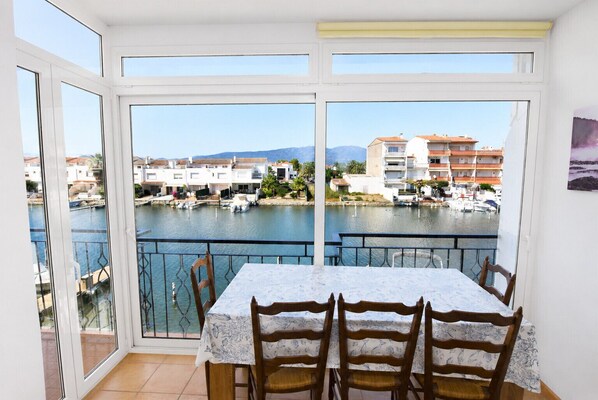 Ein Balkon mit Tisch und Stühlen, der auf einen Yachthafen mit Booten und Gebäuden blickt.