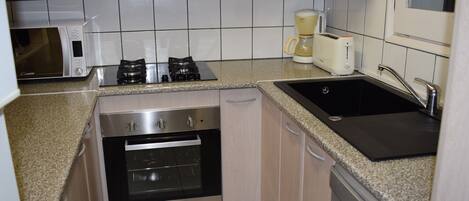Una cocina compacta equipada con microondas, estufa, horno, cafetera y lavavajillas.