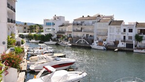 A marina with boats docked, a white building with balconies, and a clear sky. - 337-Nice apartment with view on the marina (Empuriabrava)