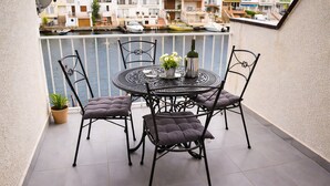 A balcony with a round table, four chairs, a potted plant, and a bottle. - 337-Nice apartment with view on the marina (Empuriabrava)