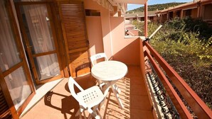 Ein Balkon mit Tisch und Stühlen, eine Glastür zum Verschieben und Blick auf eine Wohngegend.