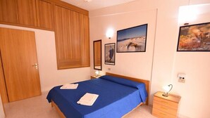 Ein Schlafzimmer mit einem großen Bett, einem Holzschrank und einem Nachttisch mit Lampe.