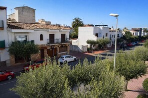 A street view with buildings, parked cars, and trees.