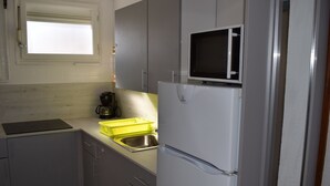 Een compacte keuken met een ingebouwde magnetron, een spoelbak en een koffiezetapparaat.