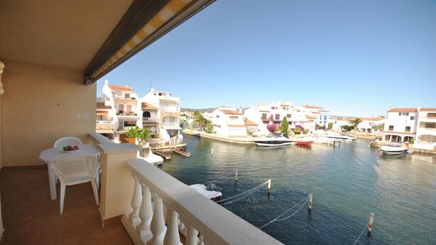 Ein Balkon mit Blick auf einen Kanal, Boote und weiße Gebäude mit roten Dächern.