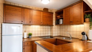 Eine Küche mit Holzausstattung, einer Edelstahl-Mikrowelle, einem Spülbecken und einem Kühlschrank.