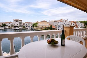 Ein Balkon mit Tisch, einer Flasche und einer Schale mit Obst.