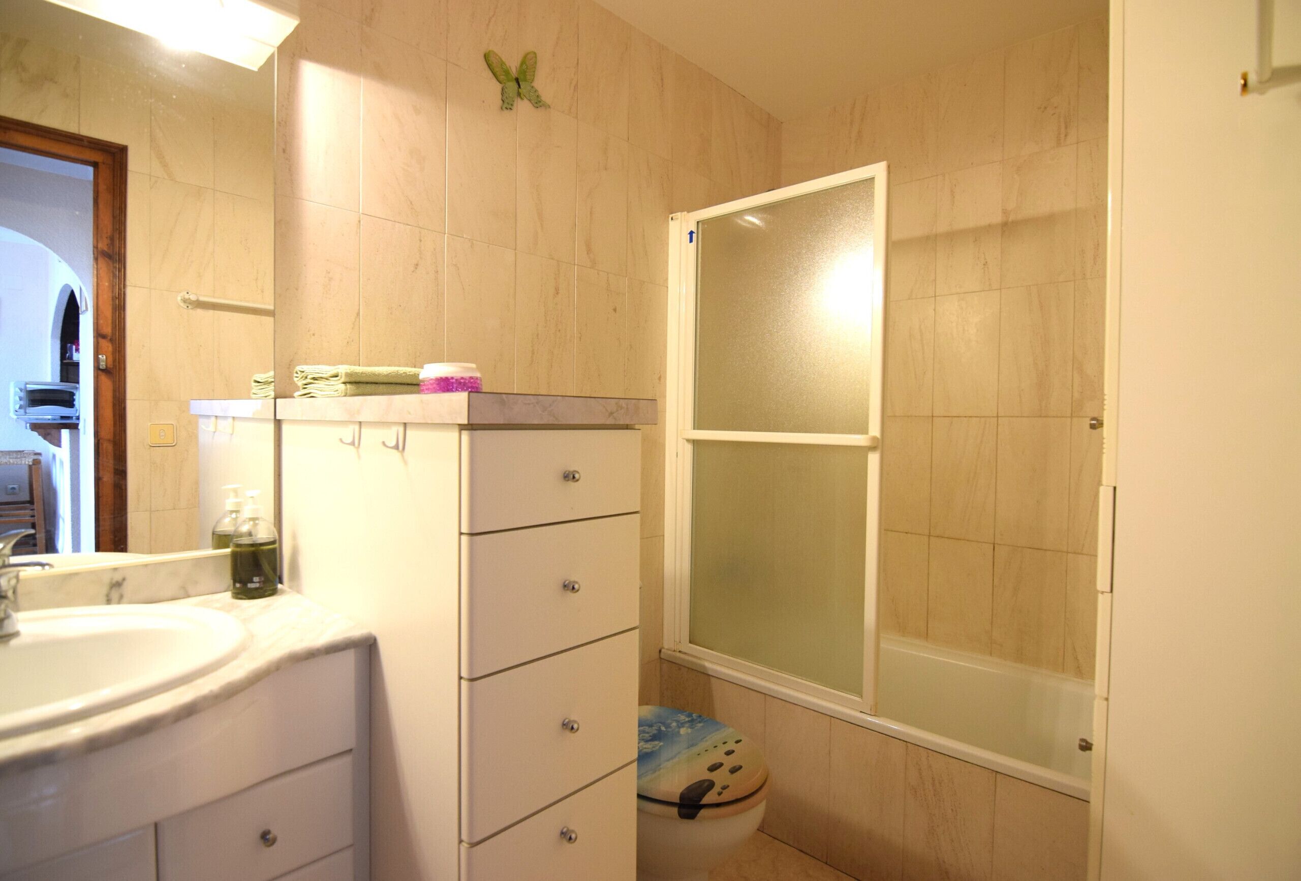 A bathroom with a sink, mirror, toilet, and shower.
