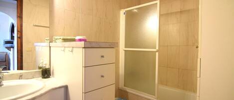 A bathroom with a sink, mirror, toilet, and shower.
