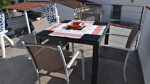 Eine Terrasse mit Esstisch und Stühlen.