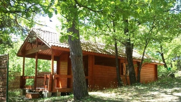 Eine rustikale Holzhütte mit Veranda, umgeben von Bäumen.