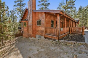 Une cabane en bois avec un porche, entourée d’arbres.