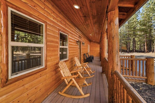 Une cabane en bois avec une véranda, des fauteuils à bascule et une vue sur la forêt.