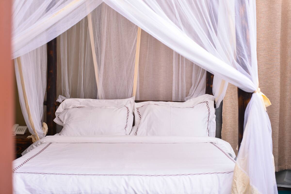 A bed with white bedding and a canopy.
