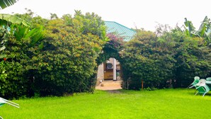 Una casa amb teulada de palla, envoltada de verdura exuberàntia i un jardí ben cuidat.