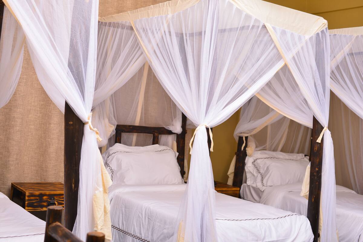 A four-poster canopy bed with white linens and a wooden frame.