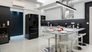A modern kitchen with a central island, white bar stools, and a black refrigerator. - Rhodes Skyline Suite - 2 Bedroom with OutDoor  jacuzzi and Sea view (Rhodes)
