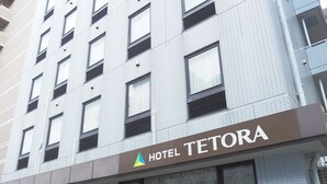 Hotel TETORA, met een moderne gevel, grote ramen en een duidelijke ingang.