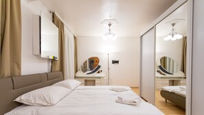 Une chambre d’hôtel moderne avec un grand lit, une coiffeuse avec un miroir et un luminaire au plafond.