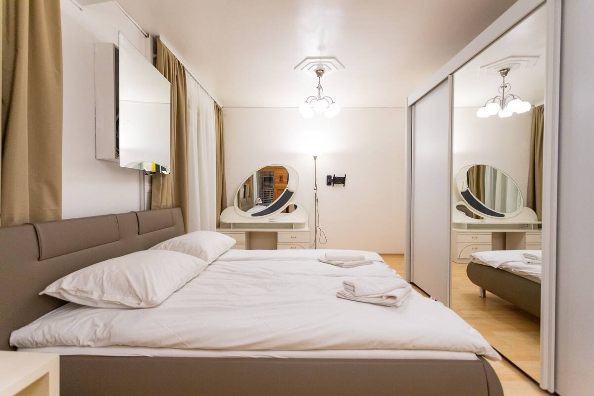 Une chambre d’hôtel moderne avec un grand lit, une coiffeuse avec un miroir et un luminaire au plafond.