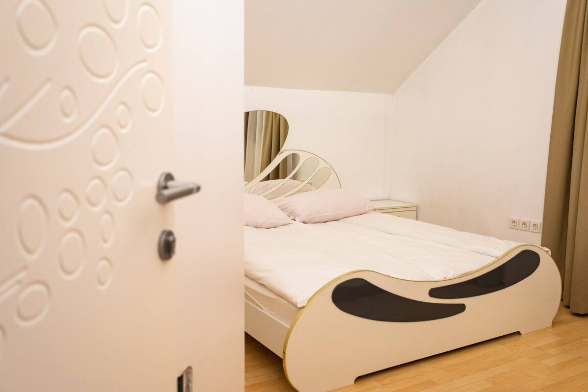 Une chambre à coucher avec un lit, une table de chevet et une porte ornée d’un motif circulaire.
