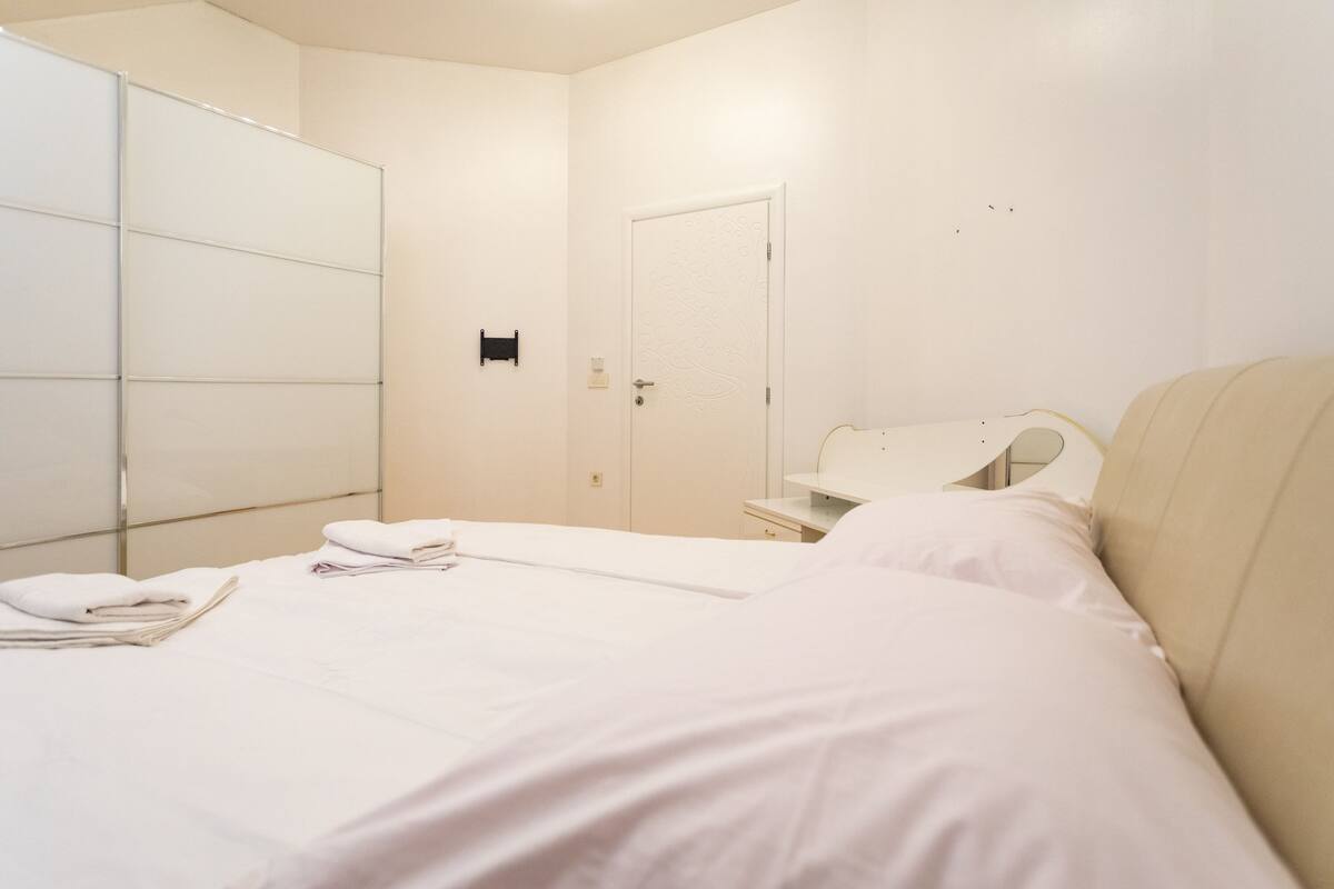 Une chambre d’hôtel avec un lit, une armoire, une porte et une petite table.