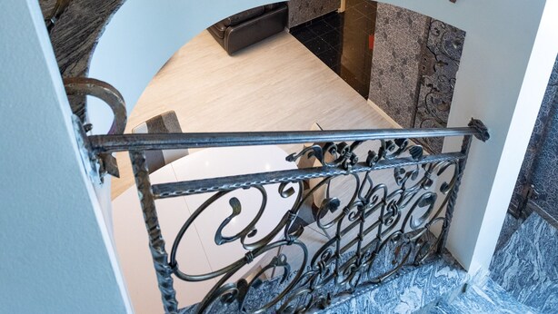 Un escalier en colimaçon agrémenté de rampes en métal ouvragé et doté d’un sol en marbre.