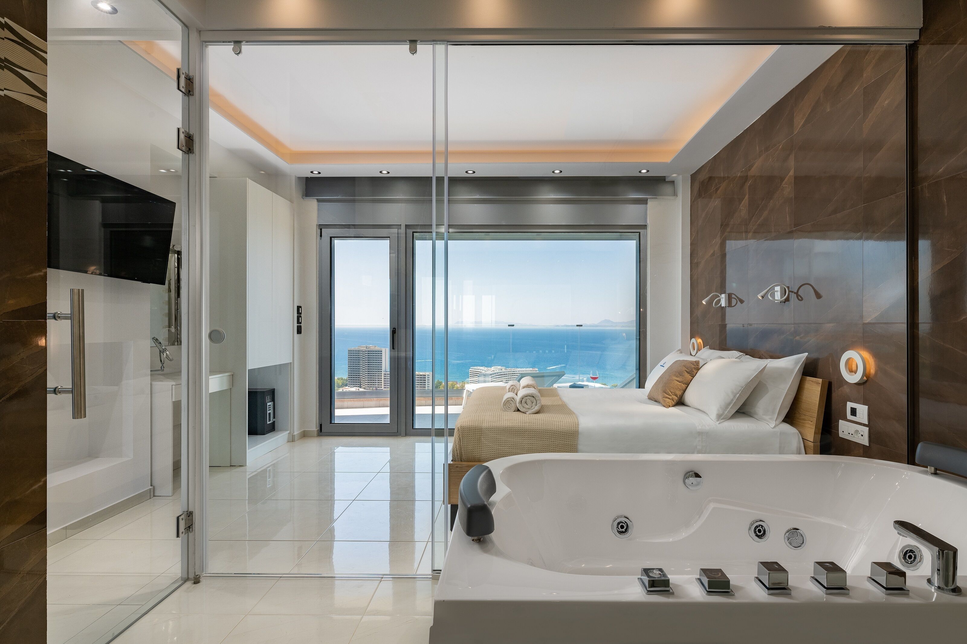 A modern bedroom with a large window, a bathtub, and a view of the city.