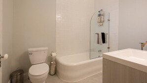 A modern bathroom with a toilet, a glass-enclosed shower, and a sink.