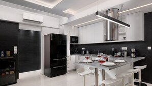 Cozinha moderna com ilha central, banquetas e geladeira preta.