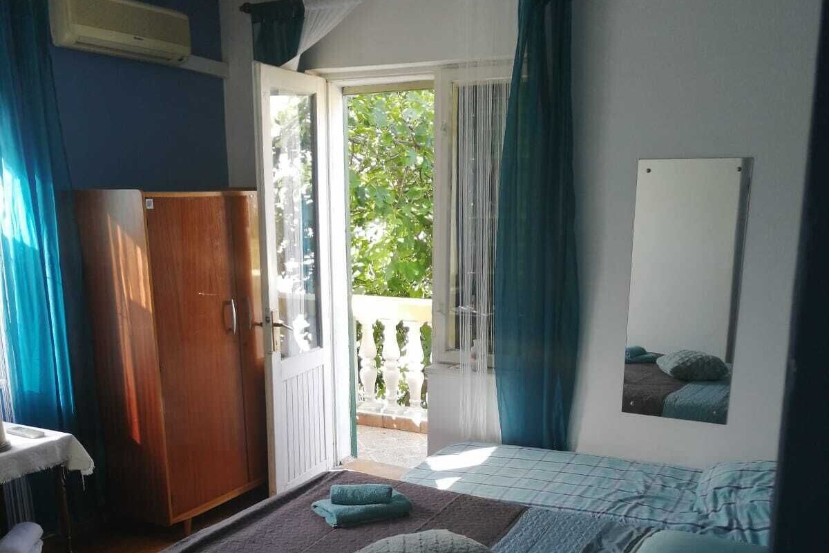 A bedroom with a bed, a wardrobe, a mirror, and a view of the outdoors.