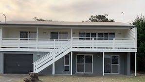Un immeuble de deux étages, doté d’un balcon à l’étage supérieur et d’un garage au rez-de-chaussée.
