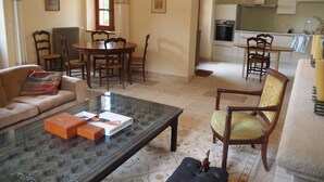 Un salon comprenant une table basse en verre, un canapé et un coin repas avec des chaises et une table en bois.